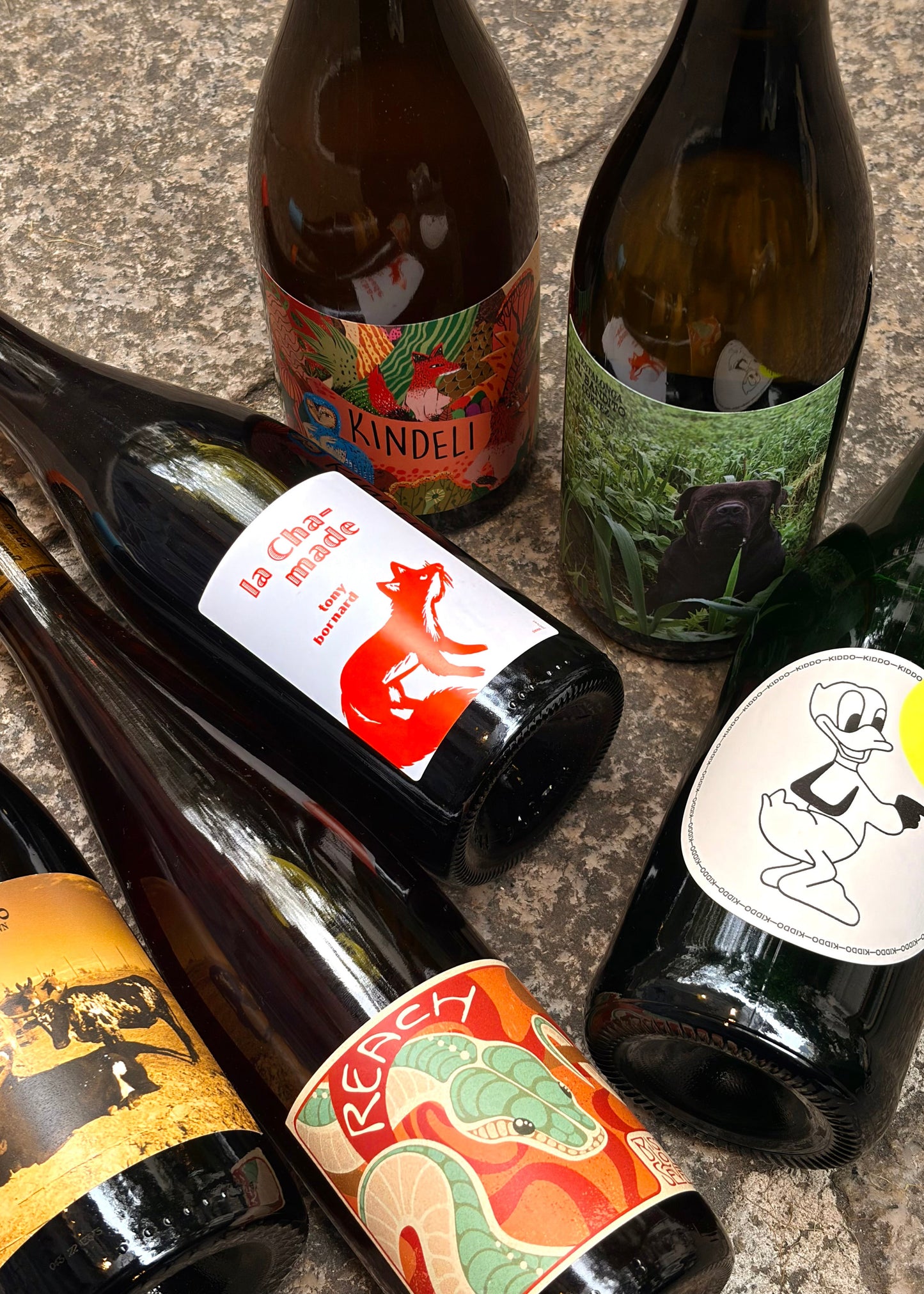 Collection of wine bottles with colorful labels on a stone surface